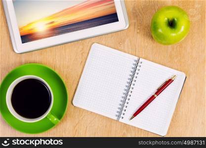 Office workplace. Tablet pc cup of coffee and notepad at table