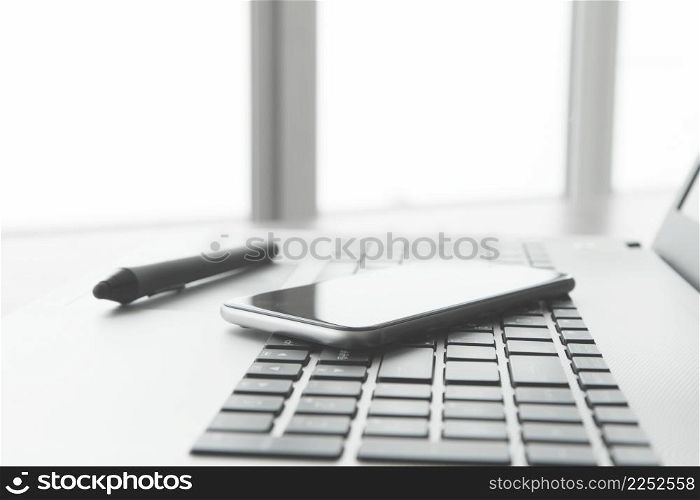 Office workplace with laptop and smart phone and stylus on wood table