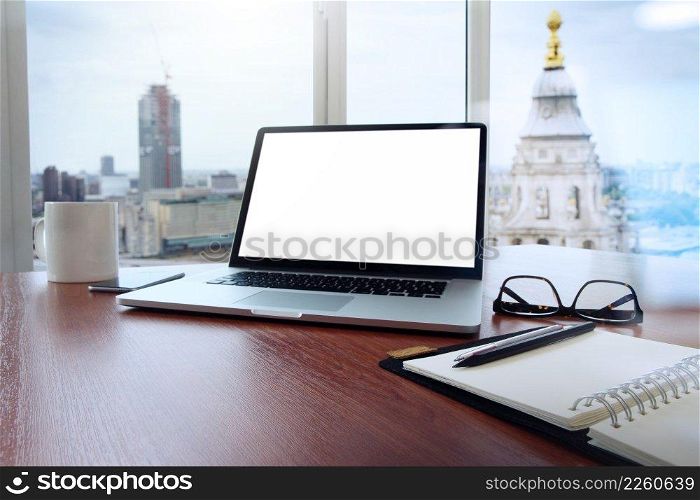 Office workplace with laptop and smart phone on wood table and london city blurred background