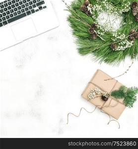 Office workplace with laptop, Christmas decoration and wrapped gift. Vintage style toned picture