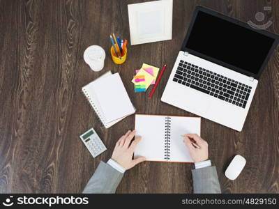 Office workplace with office supplies and laptop. Laptop and office supplies on the wooden table as seen from above