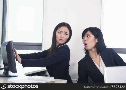 Officer worker hiding her computer from coworker