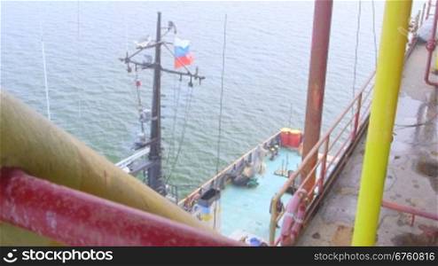 Offshore gas production platform in the East-Kazantip field, ship moored with Russian flag