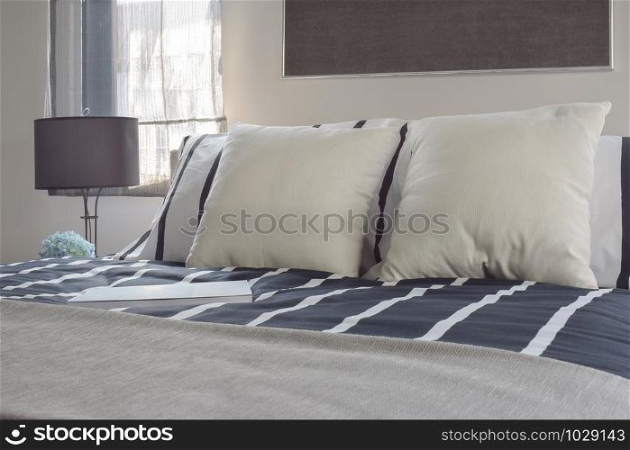 Offwhite and striped pillows on bed with deep blue striped blanket in modern style bedroom