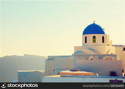 Oia town on Santorini island, Greece at sunset. Traditional and famous church with blue domes over the Caldera, Aegean sea