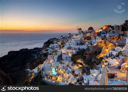 Oia town on Santorini island, Greece at sunset. Traditional and famous windmills on cliff over the Caldera, Aegean sea.