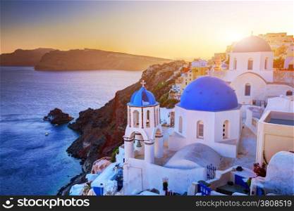 Oia town on Santorini island, Greece at sunset. Traditional and famous churches with blue domes over the Caldera, Aegean sea