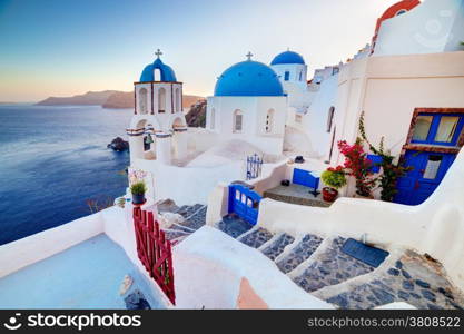 Oia town on Santorini island, Greece at sunset. Traditional and famous churches with blue domes over the Caldera, Aegean sea