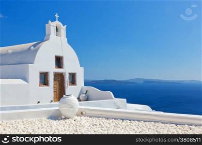 Oia town on Santorini island, Greece. Traditional church and vase over the Caldera, Aegean sea