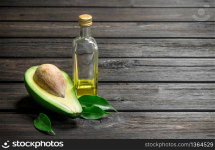 Oil and avocado with foliage. On a black wooden background. Oil and avocado with foliage.