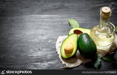 Oil and avocados. On a black wooden background.. Oil and avocados. On black wooden background.
