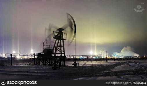 Oil and gas industry. Panoramic of a pumpjack on a oilfield and oil refinery on the winter sky background with light pillar effect . Night view. Petroleum concept.. Winter night view pump jack. Extraction of oil.