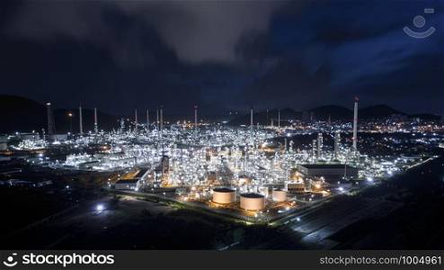 oil and gas tanker with pipeline stainless in refinery zone factory in Thailand at night over lighting blur blue sky background aerial view