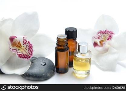 oil bottles and pebbles with beautiful orchids on white background. oil bottles and pebbles with beautiful orchids