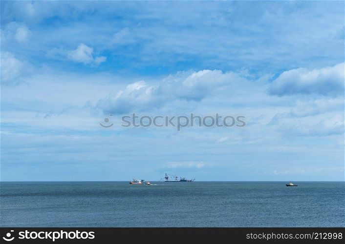 oil drilling in the sea, ships in the sea on the horizon, calm and cloudy sky. ships in the sea on the horizon, oil drilling in the sea, calm and cloudy sky