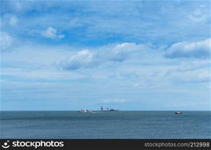 oil drilling in the sea, ships in the sea on the horizon, calm and cloudy sky. ships in the sea on the horizon, oil drilling in the sea, calm and cloudy sky