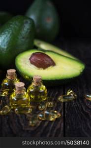 Oil of avocado and fish oil. Oil of avocado with fish oil pills on a dark wooden background