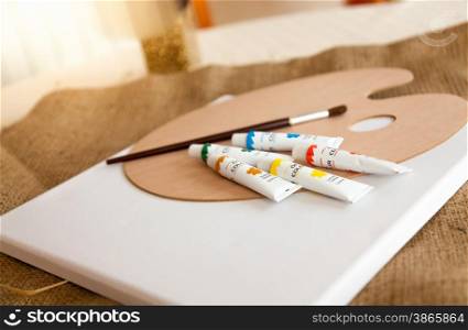 Oil paint tubes, pallet and brush lying on table at living room
