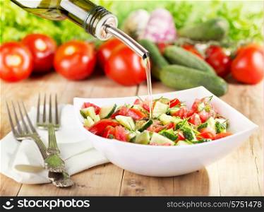 oil pouring into bowl of vegetable salad
