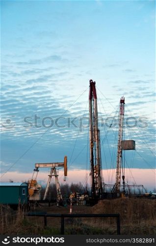 oil pump and drilling rigs at the sunset sky background. Russia, Western Siberia