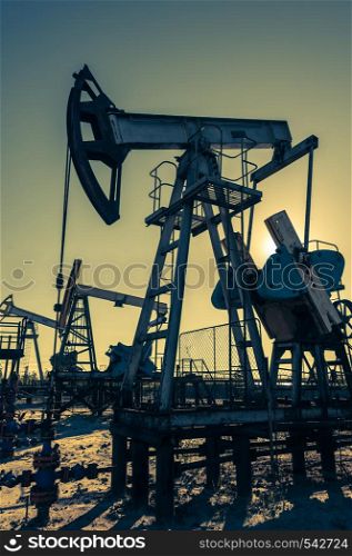 Oil pump, industrial equipment on sunset sky background. Rocking machines for extraction of oil. Mining. Petroleum concept.. Oil pump, industrial equipment. Rocking machines for extraction of oil. Mining. Petroleum concept.