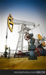 Oil pump jack and wellhead in the oilfield. Oil pump jack and wellhead in the oilfield. Oil and gas concept.