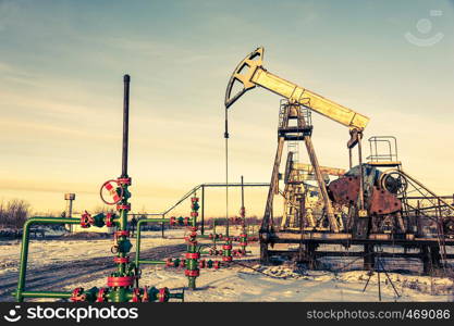 Oil pump jack and wellhead on an oil field. Mining and petroleum industry. Power generation concept. Oil and gas industry theme.. Oil pump jack and wellhead on an oil field. Mining and petroleum industry. Power generation concept.