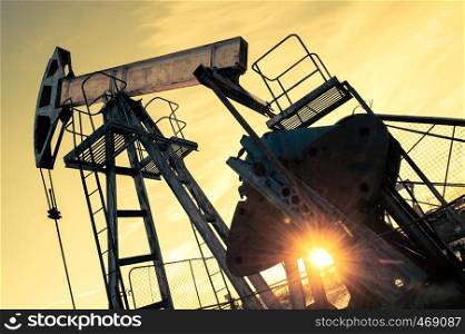 Oil pump jack and wellhead on an oil field. Mining and petroleum industry. Power generation concept. Oil and gas industry theme.. Oil pump jack and wellhead on an oil field. Mining and petroleum industry. Power generation concept.