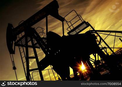 Oil pump jack on a oil field. Sunset sky background. Extraction of oil. Petroleum concept. Toned.. Pump jack. Extraction of oil. Petroleum concept.