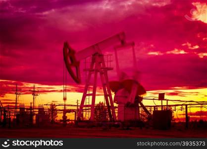 Oil pump jacks at sunset sky background. Oil and gas industry. Blurred motion. Toned.