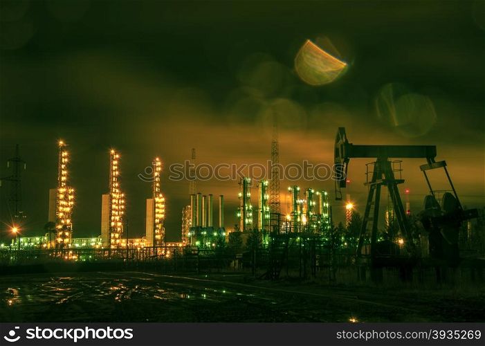 Oil rigs and brightly lit industrial site at night. Toned.