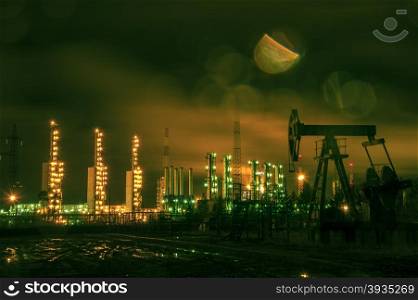Oil rigs and brightly lit industrial site at night. Toned.