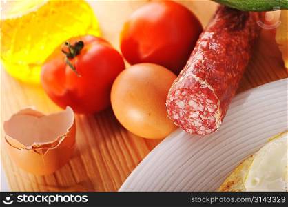 Oil, sausage and tomatoes lie near to plate