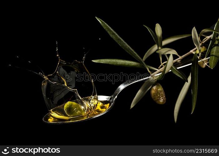 oil spoon with an olive splashing on black background