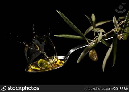 oil spoon with an olive splashing on black background