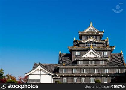 Okayama castle black Samurai fortress with blue bright sky in autumn. Japan Edo Historic castle