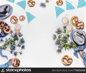 Oktoberfest background. Mugs of beer, Bavarian hats with feather, pretzel, woman hands in traditional blue blouse and alpin flowers. Top view. Modern. Flat lay. Copy space. Frame