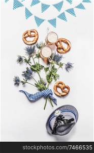 Oktoberfest composition with traditional Bavarian white blue fabric , decoration, pretzel , cups of draft beer, Bavarian hat and bunch of alpine flowers on white background. Top view. Flat lay