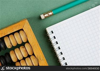 old abacus and notebook on the green background