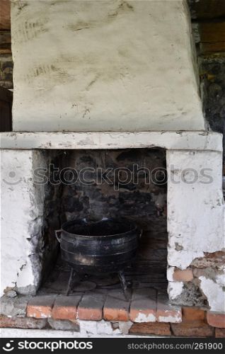 Old abandoned indoors fireplace with an old iron pot