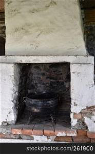 Old abandoned indoors fireplace with an old iron pot