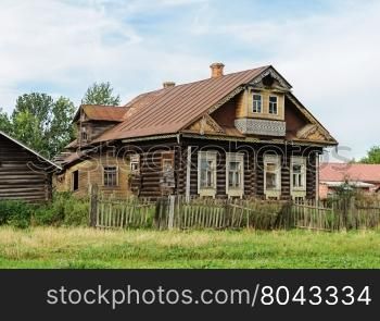 Old abandoned log wooden house with balcony. Summer day