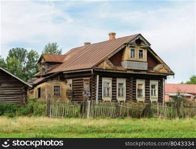 Old abandoned log wooden house with balcony. Summer day