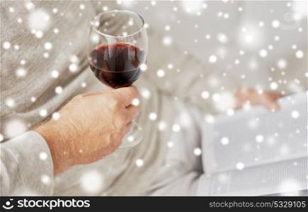 old age, alcohol and people concept - close up of senior man with red wine glass and book over snow. close up of senior man with wine glass and book