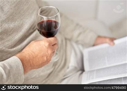 old age, alcohol, leisure and people concept - close up of senior man with red wine glass and book