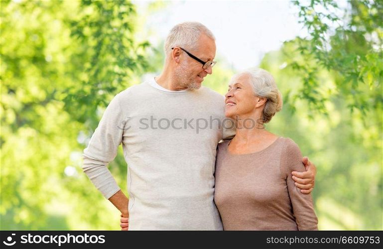 old age and people concept - happy senior couple hugging over green natural background. senior couple hugging over natural background