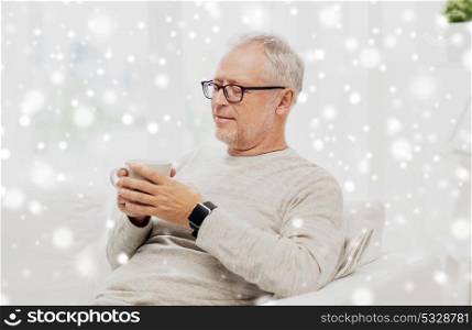 old age and people concept - happy senior man with cup of tea at home over snow. happy senior man with cup of tea at home