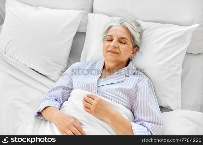 old age and people concept - happy senior woman sleeping in bed at home bedroom. happy senior woman sleeping in bed at home bedroom