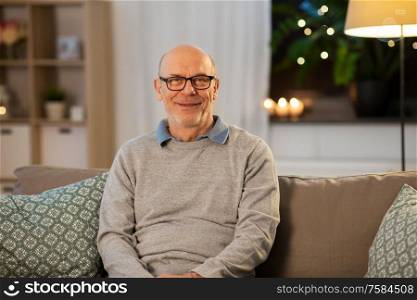 old age and people concept - happy smiling senior man in glasses at home in evening. happy smiling senior man in glasses at home