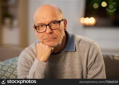 old age and people concept - sad senior man in glasses thinking at home in evening. sad senior man in glasses thinking at home